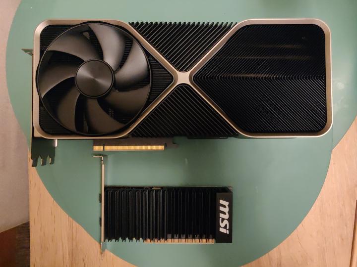 An RTX 4090 GPU laying besides a much smaller a GT 1030